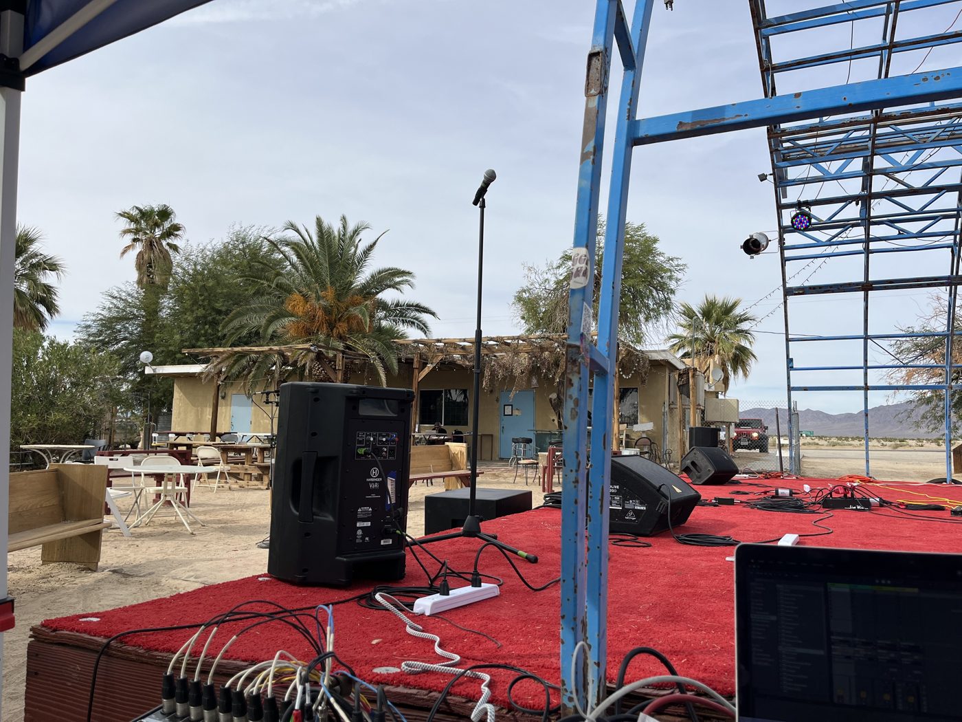 Outdoor stage with loudspeakers and microphone stand in the desert, seen from the mixing position